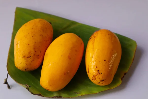 Beyaz Arka Planda Izole Edilmiş Muz Yapraklı Olgun Sarı Mango — Stok fotoğraf