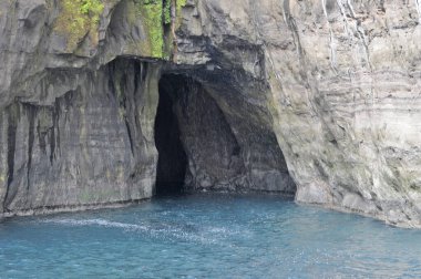      Vgar Adası 'ndaki ünlü SpireTrllkonufingur' un yakınındaki kayalıklar ve mağaralar.                          