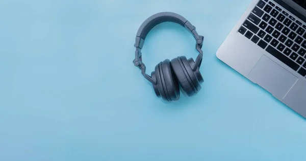 blue desk of student with laptop and black headphone, right side negative space, top view