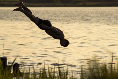 Yazın nehre atlayan bir adamın silueti. 