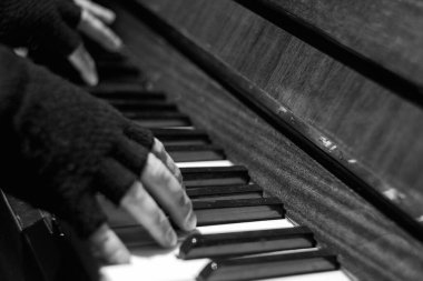 Piyanistin elleri siyah eldivenlerle piyanoda müzik çalarken, enstrümanın anahtarları siyah ve beyaz.