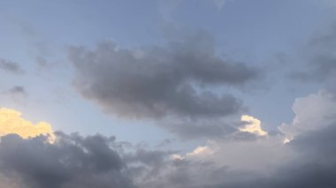 Parçalı bulutlu bir gökyüzü ve portakal rengi ışığın içinden süzülüşü.