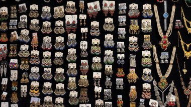 Değişik bir geleneksel Hint mücevheri koleksiyonu yakalar. Karmaşık tasarlanmış küpeler ve siyah bir arka plana karşı çarpıcı kolyeler sergiler..