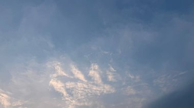 Manzaralı bir manzara, ince ince bulutlarla süslenmiş açık maviden daha derin renklere bir gradyanı yakalar. Bu huzurlu gökyüzü sabahın erken saatlerinde ya da alacakaranlıkta.