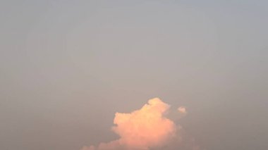Tek, tüylü bir bulut pembe ışıkla aydınlanır yumuşak, soluk gri ve pembe bir gökyüzüne karşı, muhtemelen alacakaranlıkta ya da şafakta. Sakin atmosfer huzuru çağrıştırıyor..