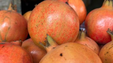 Canlı bir yakın plan, derilerinin benekli dokusunu ve renk değişimlerini vurgulayan bir yığın nar sergiliyor. Basit bir çekimde tazeliklerini ve doğal cazibelerini vurguluyorlar..