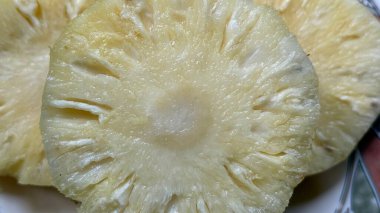 Bu yakın çekim olgun bir ananas diliminin karmaşık detaylarını ve dokularını gözler önüne seriyor. Sulu sarı hamuru ve lifli çekirdeği çeşitli kullanımlar için görsel olarak çekici bir görüntü oluşturur..