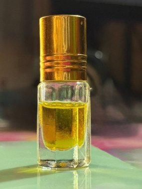 Hareketsiz yaşam kısa, kare cam bir şişe gösteriyor. Sarı bir sıvıyla doldurulmuş, altın kaplamalı, soluk yeşil bir yüzeye yerleştirilmiş, koyu, bulanık bir zemin.