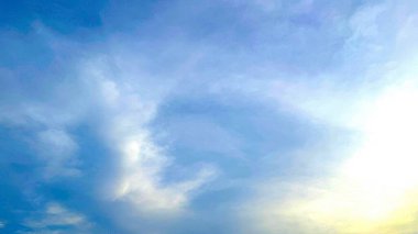 Huzurlu bir manzara, yumuşak, yastık gibi beyaz bulutlarla dolu gökyüzünü gösteriyor. İçinden süzülen canlı mavi renkler. Parlak güneş ışığı sahneyi güçlendirir.