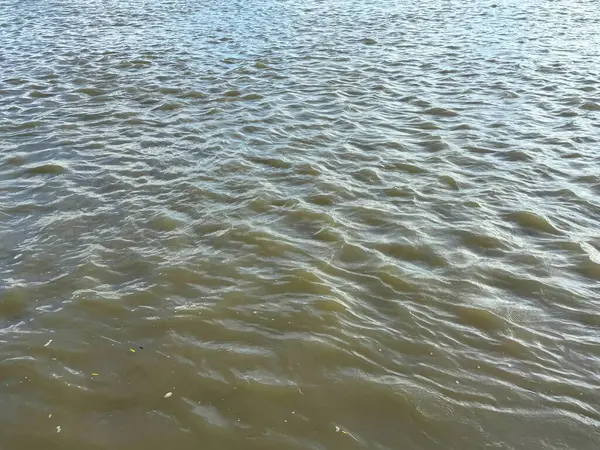 Tam kare yüksek çözünürlüklü fotoğraf dalgaları bulanık suyu yansıtıyor güneş ışığını yansıtıyor, suyun yüzeyinde karmaşık dalga desenleri yaratıyor, dinamik bir dokuyla sonuçlanıyor..