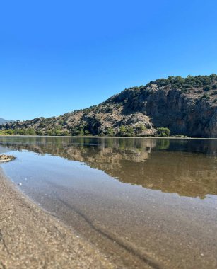 Kum nehri ve doğa okyanusu, yeşil kum, mavi gökyüzü, dağ ormanı, nehir kenarına bakar.