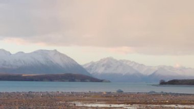 Tekapo Gölü, Yeni Zelanda 'nın bir görüntüsü. Ön planda göl ve arka planda karlı dağlar var..