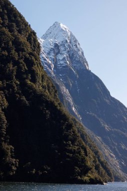 Mitre tepesi başka bir tepenin arkasından çıkıyor. Mitre zirvesi Milford Sound, Yeni Zelanda 'da bulunur ve karla kaplıdır.