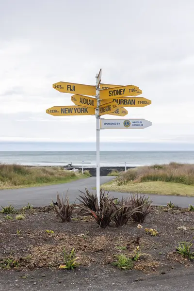 A photo of a street sign post that is faumous around New Zealand. Around the country there are several other versions of this post. This post is located on the east coast of the north island of New Zealand just out side of New Plymouth. The sign cont