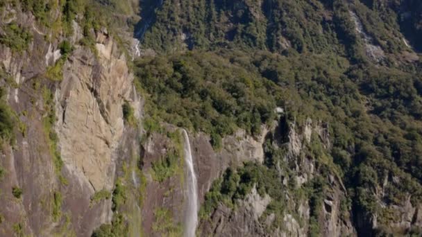 広いパンニングと滝の傾斜 それはニュージーランドのミルフォードサウンドの雪の山のトップソースです — ストック動画
