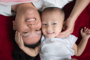 Anne ve çocuk gülümseyen yüzlerle uzanıyorlar, neşeli bir ruh hali içinde birbirleriyle oynuyorlar. Sağlık konsepti, sağlık sigortası, aile ilişkilerinin geliştirilmesi.