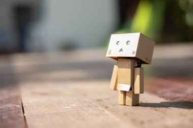 Küçük tahta oyuncak robot danbo yalnız başına yalnız başına üzgün karakter, ahşap zemin çizgi film kutusu anime mutlu sanat konsepti yaz, kahverengi oyuncak bebek ruh hali yalnızlık duygusu renkli tatil