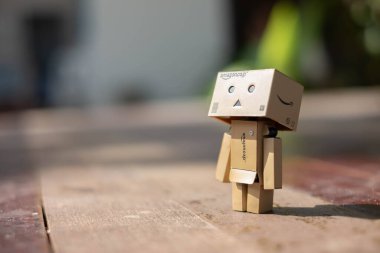 Küçük tahta oyuncak robot danbo yalnız başına yalnız başına üzgün karakter, ahşap zemin çizgi film kutusu anime mutlu sanat konsepti yaz, kahverengi oyuncak bebek ruh hali yalnızlık duygusu renkli tatil