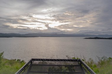 Güzel doğa gölünde gün batımında hamakla seyahat etmek, manzara gökyüzü ve akşam güneş ışığıyla tatil yapmak, sakin, bulutlu arka plan manzaralı, sakin bir ufuk.