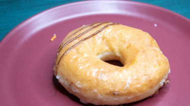 Üzerine karamel sosu serpiştirilmiş taze bir çörek ve pudra şekeri, kırmızı bir tabakta servis edilir..