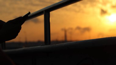 Bulutlu bir gün batımında bir direğin yanında bir insanın siluetinin yakın çekim görüntüsü..