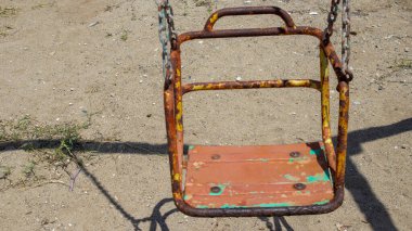 Kumsalda terk edilmiş parkta paslı bir oyuncak.