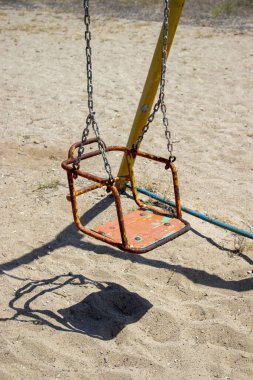 Kumsalda terk edilmiş parkta paslı bir oyuncak.