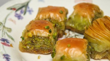 Beyaz tabakta taze Türk baklavası ve gün ışığında çiçek desenleri