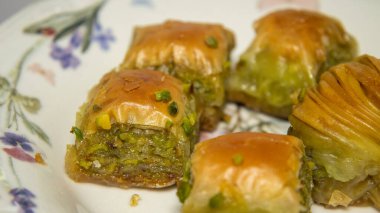 Beyaz tabakta taze Türk baklavası ve gün ışığında çiçek desenleri