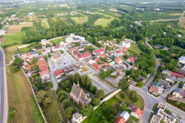 Polonya 'da bulutlu bir gökyüzünün altında yeşilliklerle çevrili küçük bir kasabanın dikey görüntüsü.