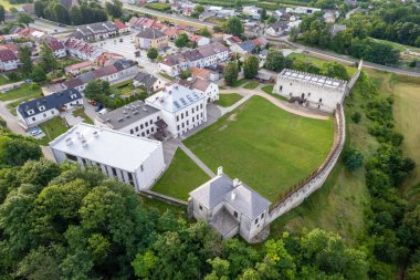 Polonya 'da bulutlu bir gökyüzünün altında yeşilliklerle çevrili küçük bir kasabanın dikey görüntüsü.