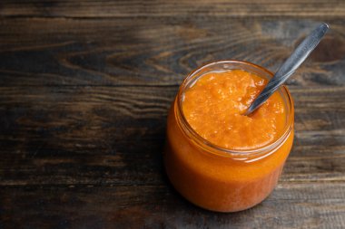 Cam kavanozda kayısı reçeli ve içinde kaşık var.