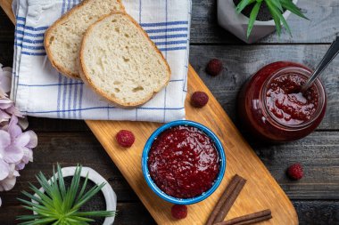 Taze ev yapımı ahududu reçeli ahşap bir tabakta, ekmek ile servis edilir.