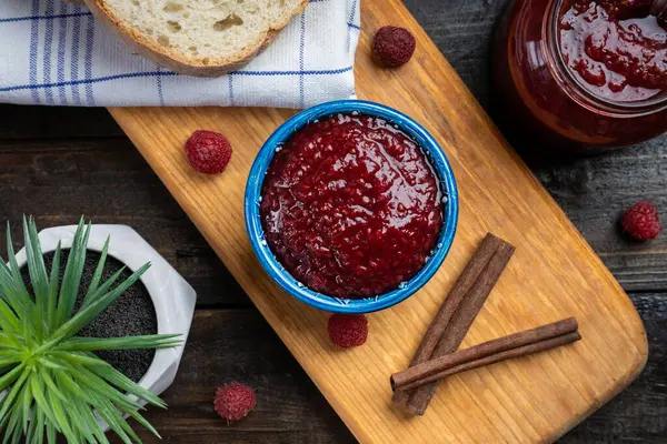 Taze ev yapımı ahududu reçeli ahşap bir tabakta, ekmek ile servis edilir.