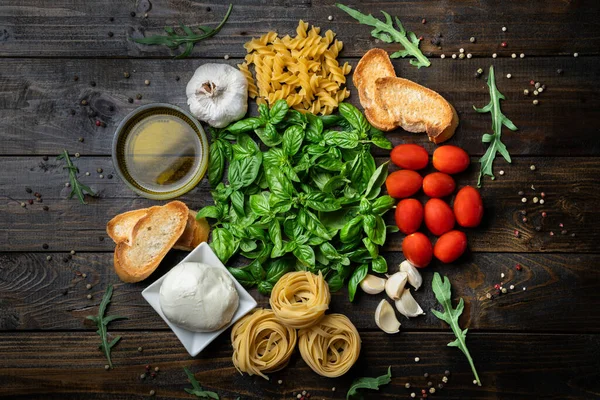 İtalyan yemek malzemeleri, taze mozzarella, bruschetta, çiğ tagliatelle ve fusilli, fesleğen yaprağı, domates, sarımsak, roka, zeytinyağı ve biber.
