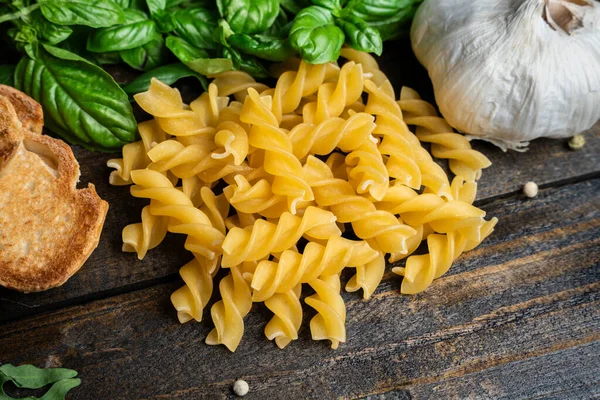 İtalyan yemek malzemeleri, taze mozzarella, bruschetta, çiğ tagliatelle ve koyu ahşap arka planda fesleğen yaprakları.