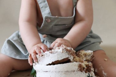 Pastayı parçala, ilk doğum gününde kekle küçük kız. Seçici odak.