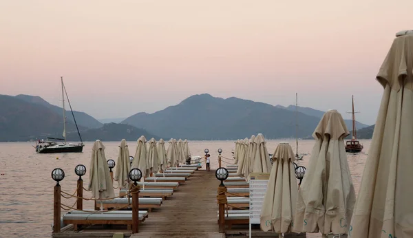 Mugla, Marmaris Turkey - 31 Temmuz 2020: Bir yaz günü altın saatinde kapalı şemsiyeli ve tekneli iskele. Seçici Odaklanma