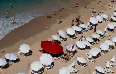 Kırmızı ve beyaz şemsiyeler. Kırmızı ve beyaz şemsiyeli kalabalık bir plajın manzarası.