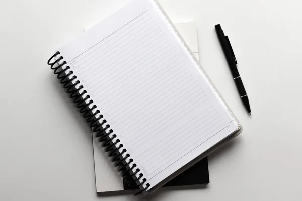 Yazı alanı olan bir ofis. Boş defterleri ve kalemi olan beyaz tablonun üst görünümü.