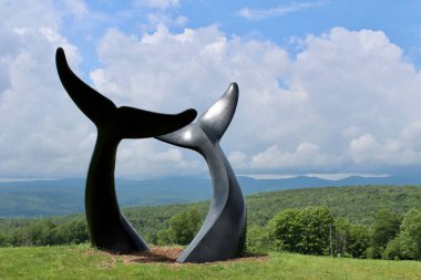 Yeşil dağların önünde balina kuyruğu heykeli