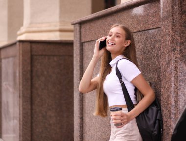 Mutlu bir öğrenci, arkadaşlarıyla çalıştıktan ve sohbet ettikten sonra bir üniversitenin yakınındadır. Bir fincan kahve ve poşeti alıyor..
