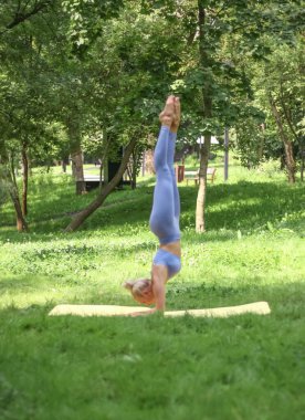 Beyaz bir kadın esneme hareketleri yapıyor, parkta yoga yapıyor. Dengeyi sağlıyorum. Spor konsepti.