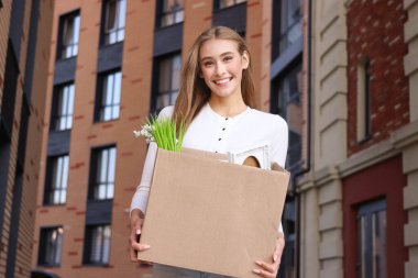 Güzel genç bir kadının portresi, apartmanın iç bahçesinde içinde dekorasyon bulunan bir kutu tutuyor. Yeni bir eve taşınıyor..