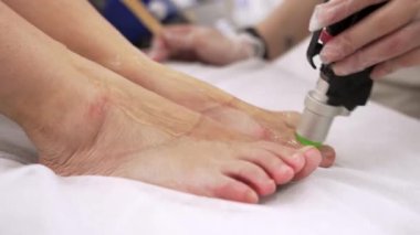 Profesyonel kozmetolojistin, güzellik salonundaki genç bayanın ayaklarına lazer kılı aldırma videosunu kapatın. Güzellik konsepti.