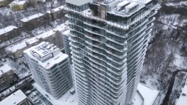 Drone view of industrial climbers in orange uniform and helmets working on high new modern building in European city in snowy winter. Dangerous work, professional climbers, alpinism