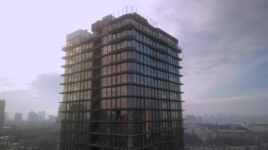 Drone view of industrial climbers in orange uniform and helmets working on high new modern building in European city. Dangerous work, professional climbers, alpinism