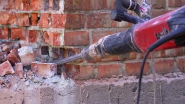 Break up, professional worker drills old brick tube with jackhammer, close up shot. Construction snd demolition concept.