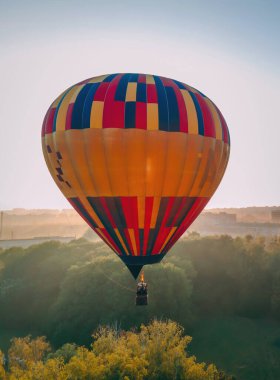 Renkli sıcak hava balonu, Ukrayna 'nın Kiev bölgesinde yaz gündoğumunda küçük Avrupa kentindeki yeşil parktan havalanıyor.