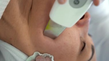 Beyaz kadın güzellik salonunda ultrasonik yüz soyma ameliyatı oluyor. Ultrasonik bir kazıyıcı ile yüzünü temizlemek. Kozmetoloji ve yüz bakımı. Yüz bakımı. 4k görüntü